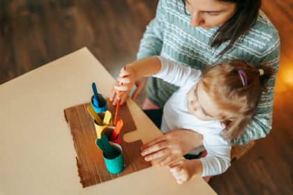 Top view of a young woman with little girl doing children activities, interesting educational games.